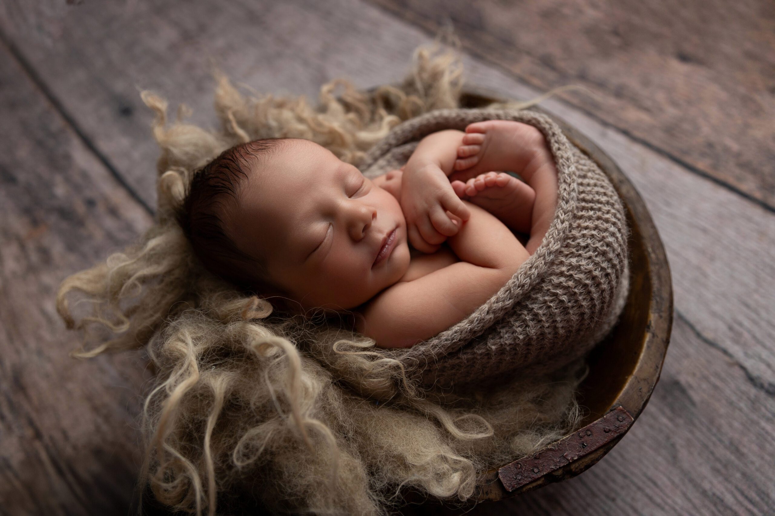 Newborn baby posed in a bowl during a studio session with a West Island newborn photographer